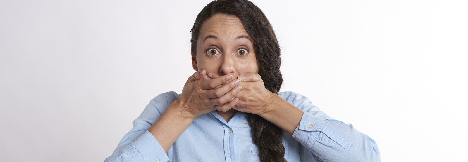 Stock photo of woman with hands over her own mouth.